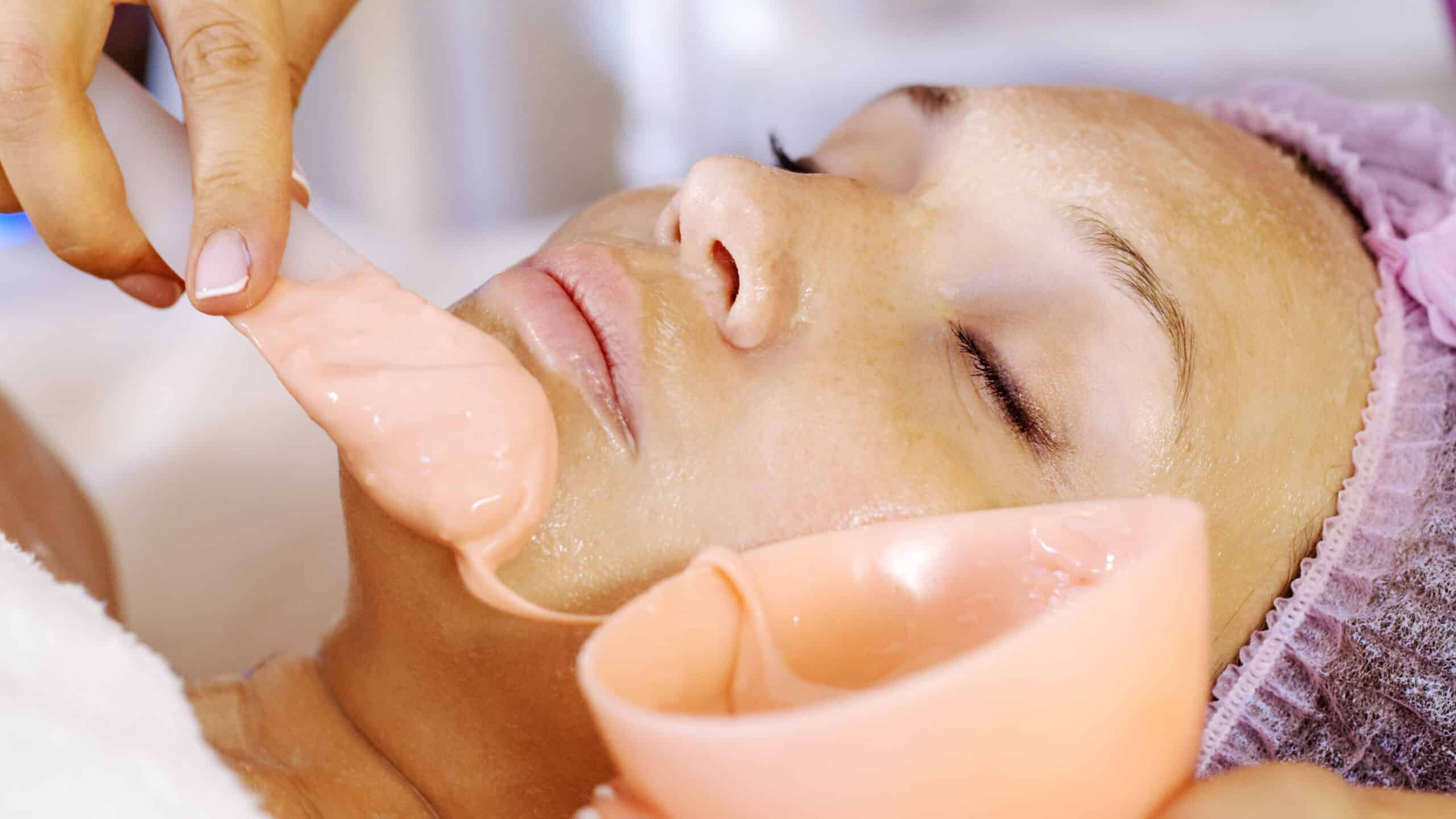 Argiloterapia Facial - Belo Horizonte 7 Cosmetologist applies a scrub on female face. Woman in a spa salon on cosmetic procedures for facial care.