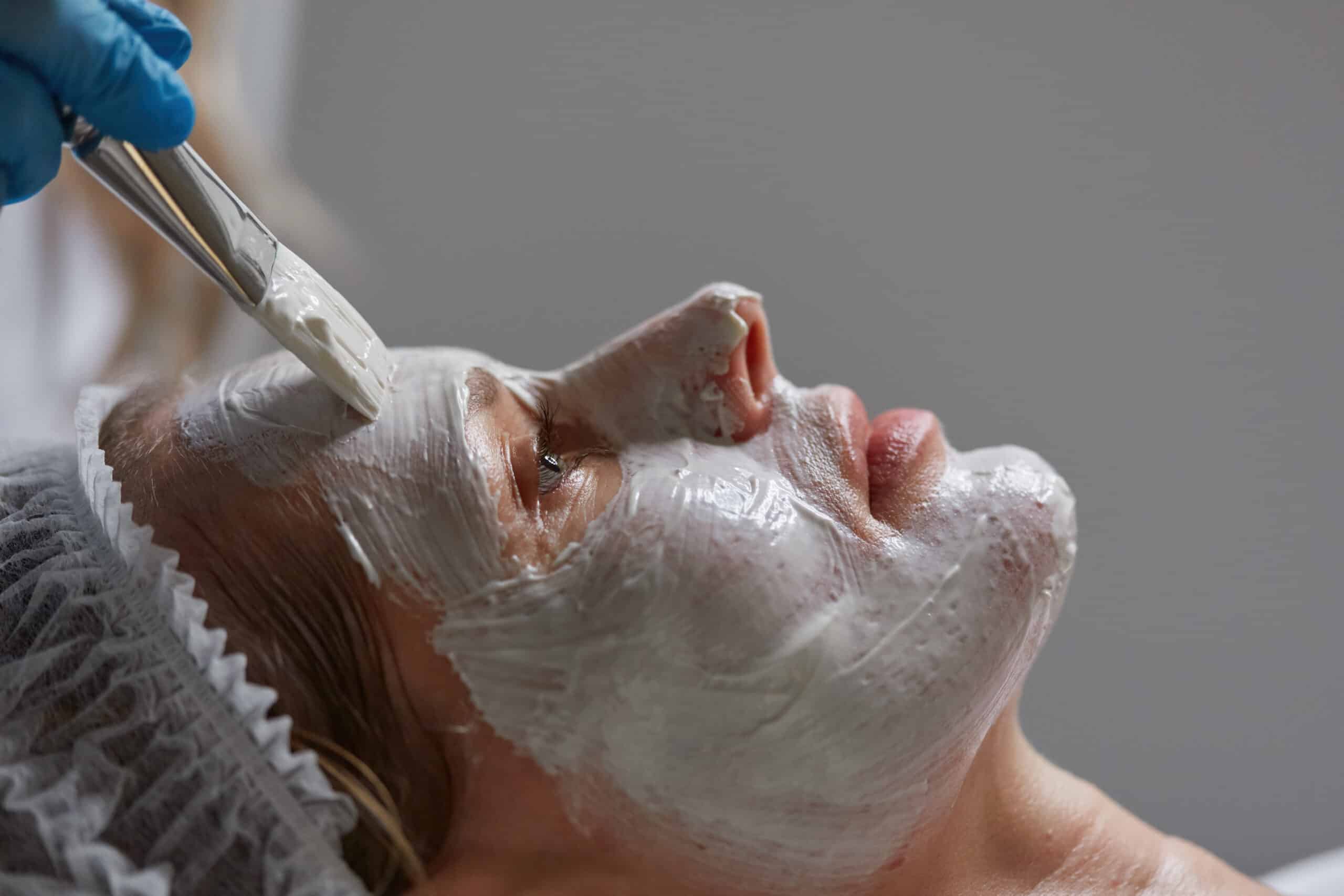 Argiloterapia Facial - Belo Horizonte 10 Closeup side view on cosmetologist brush applying clay mask on female client face