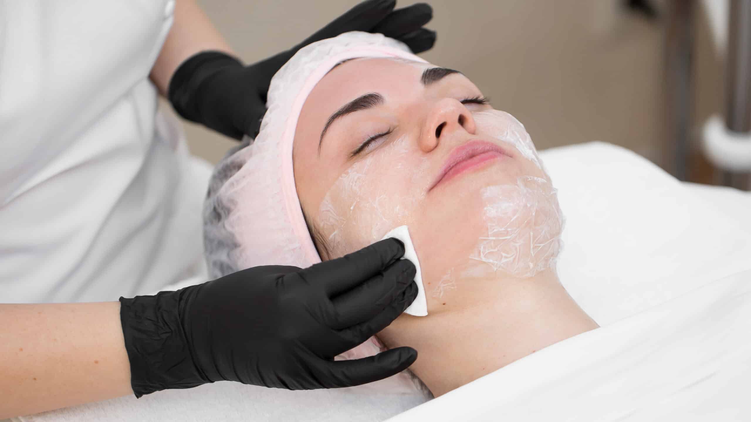 Close-up beautician wipes white cotton swabs face of a young girl before the cosmetic rejuvenation procedure